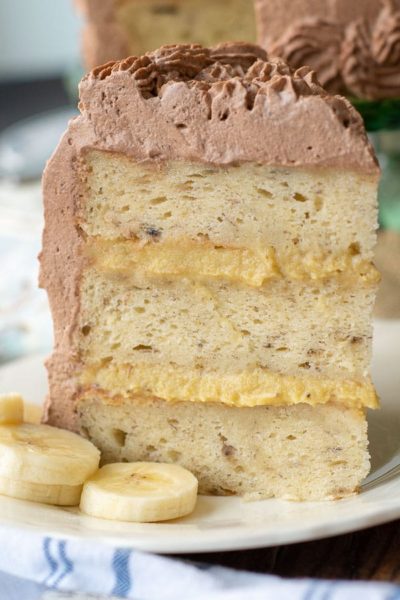 a piece of fluffy banana cake with banana filling standing straight up on a plate