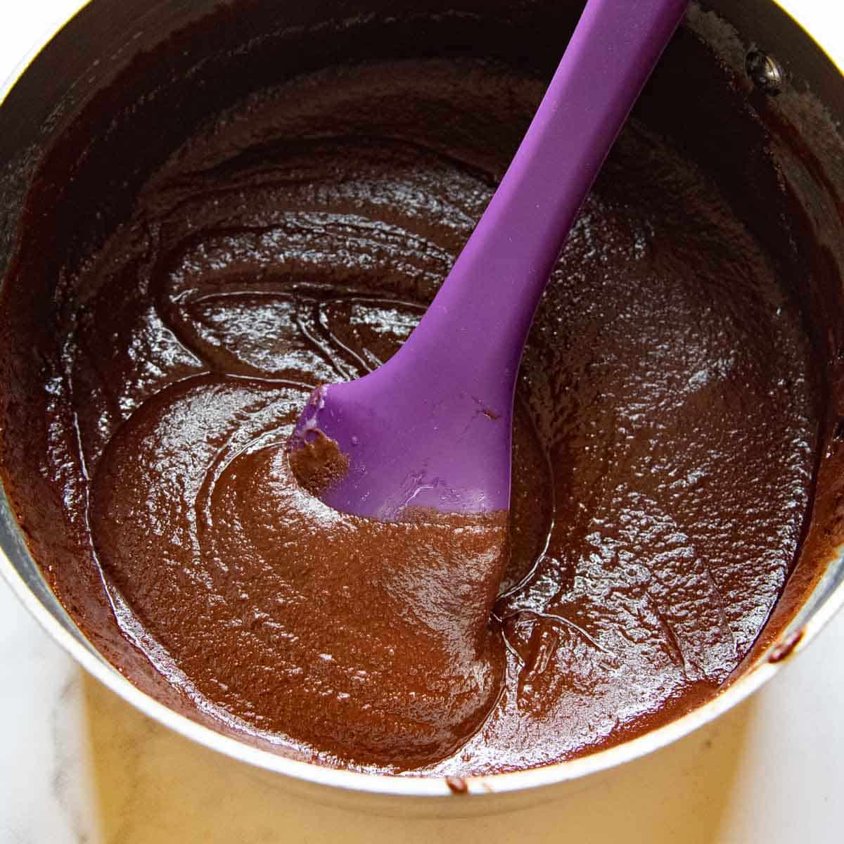 a purple spoon stirring a chocolate mixture.