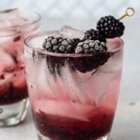 a picture of blackberry cocktail with fresh berries on a pick sticking out of the glass