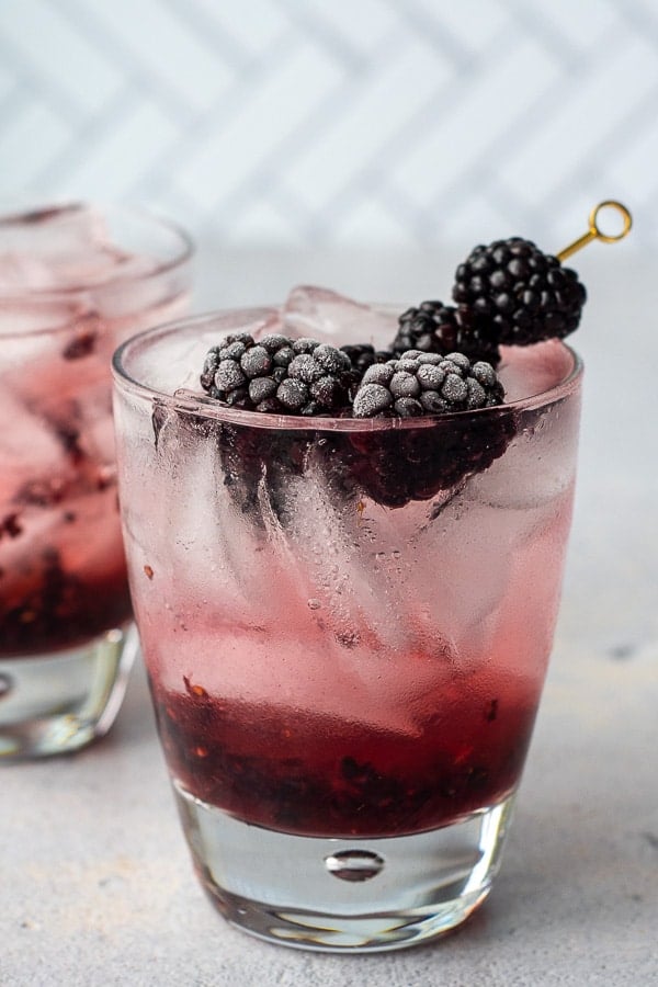 a picture of blackberry cocktail with fresh berries on a pick sticking out of the glass