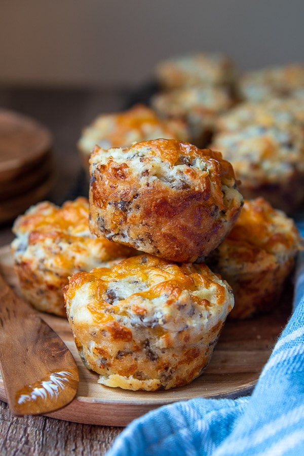 a plate of sausage muffins piled on a wood plate