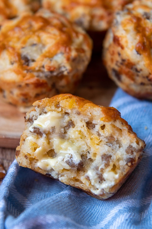 a sausage cheese muffin ripped in half with melting butter spread on