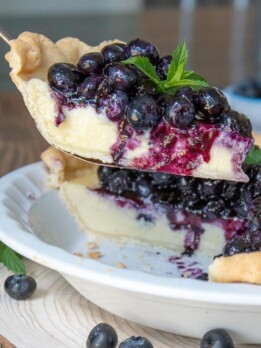 a pie server lifting a slice of blueberry cream pie out of a pie dish