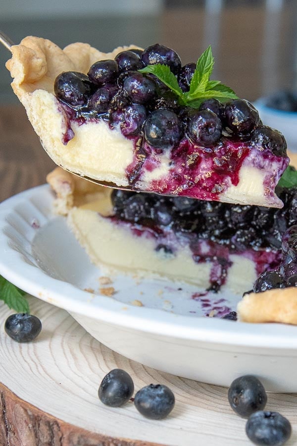 a pie server lifting a slice of blueberry cream pie out of a pie dish