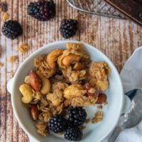 a bowl of homemade granola with milk and berries