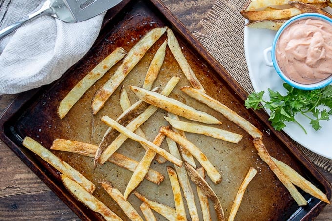 an overhead shot of a pan of baked fries with a spatula resting next to it
