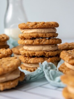 a stack of three cookie sandwiches with a milk bottle in background