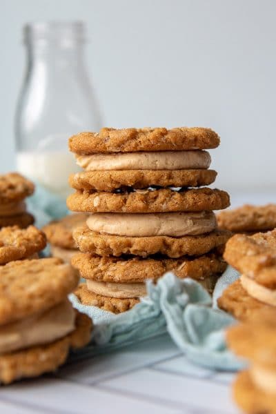 a stack of three cookie sandwiches with a milk bottle in background