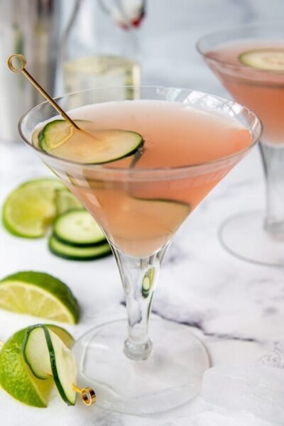 a pink cucumber cosmo with another drink and martini shaker in the background