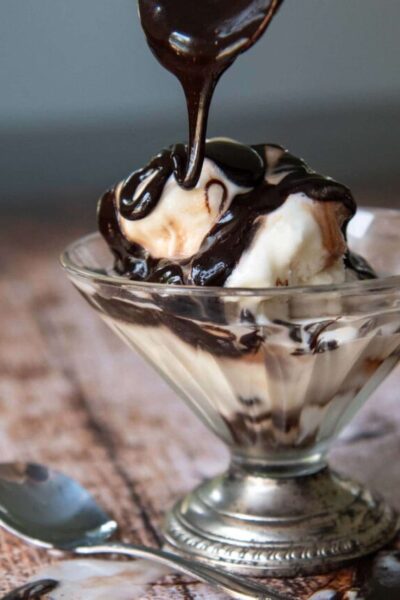 chocolate syrup on melting ice cream in a footed dish