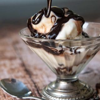 chocolate syrup on melting ice cream in a footed dish