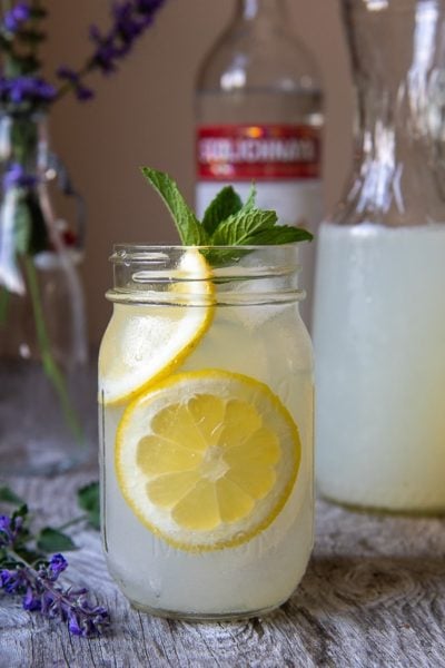 straight on shot of spiked lemonade with sliced lemons in a jar glasses