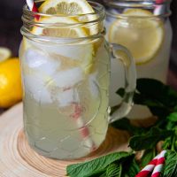 lemon shake-up in jar glass on a wooden circle with red and white straws