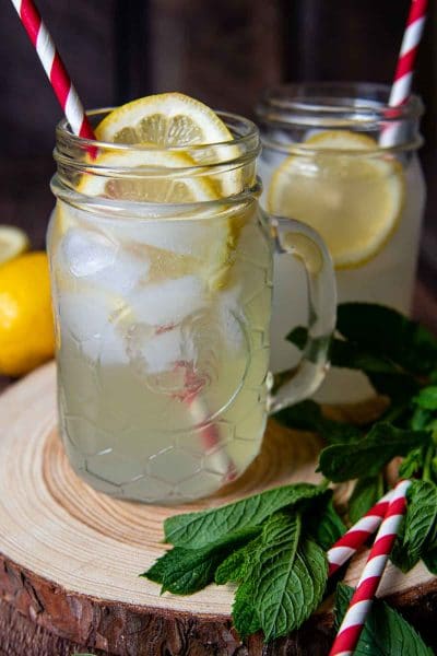 lemon shake-up in jar glass on a wooden circle with red and white straws