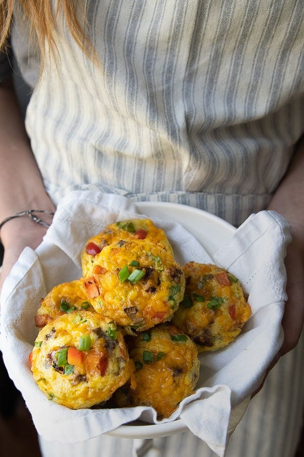 someone holding a bowl of egg muffins ready to be served
