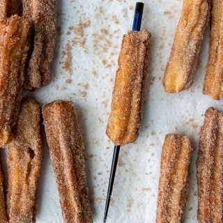 a chopstick going through cooked churros to make an opening for filling
