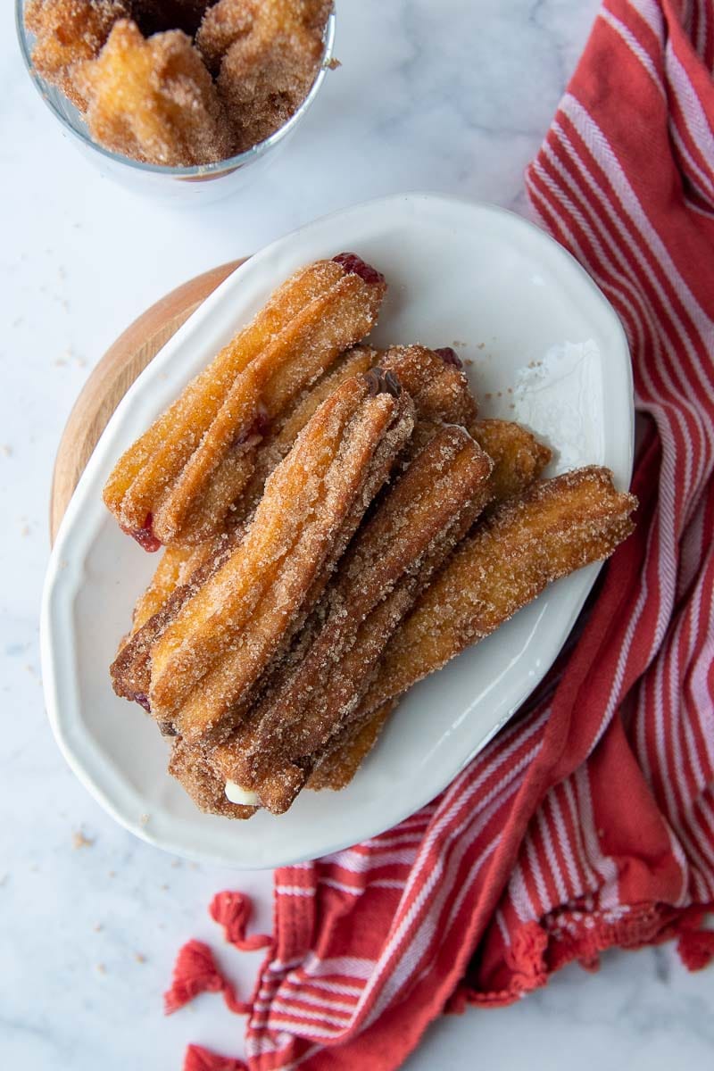 overhead shot of gluten free churros on a white plate with a red dish towel next to it
