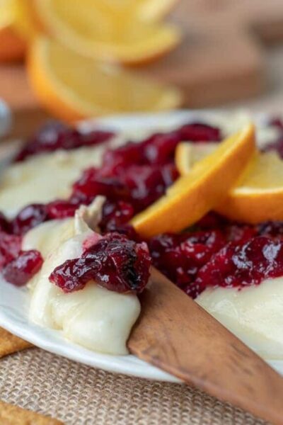 a wooden knife cutting into cranberry baked brie