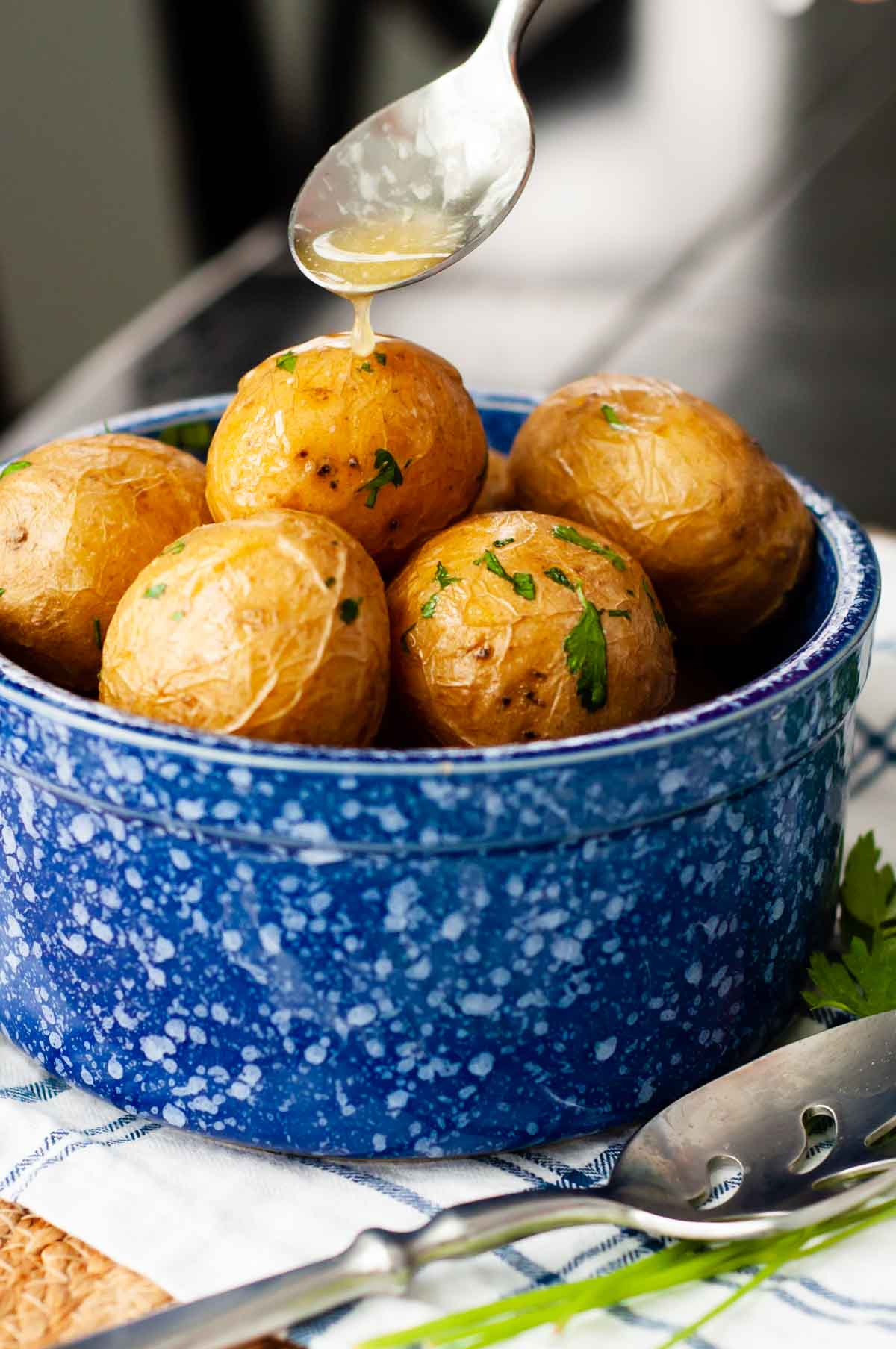 butter being spooned over a bowl of salt potatoes