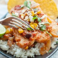 a fork about to cut into a plate of mexican fish served on rice