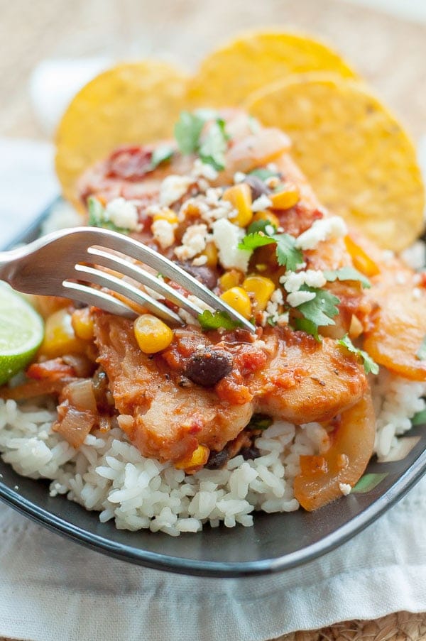 a fork about to cut into a plate of mexican fish served on rice