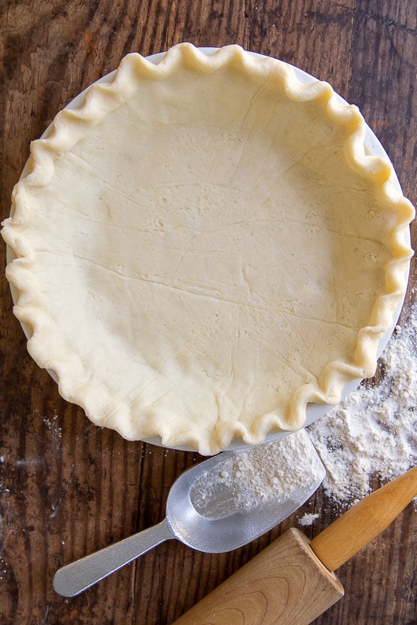 overhead shot of unbaked gluten-free pie crust with a rolling pin and flour sprinkled next to it