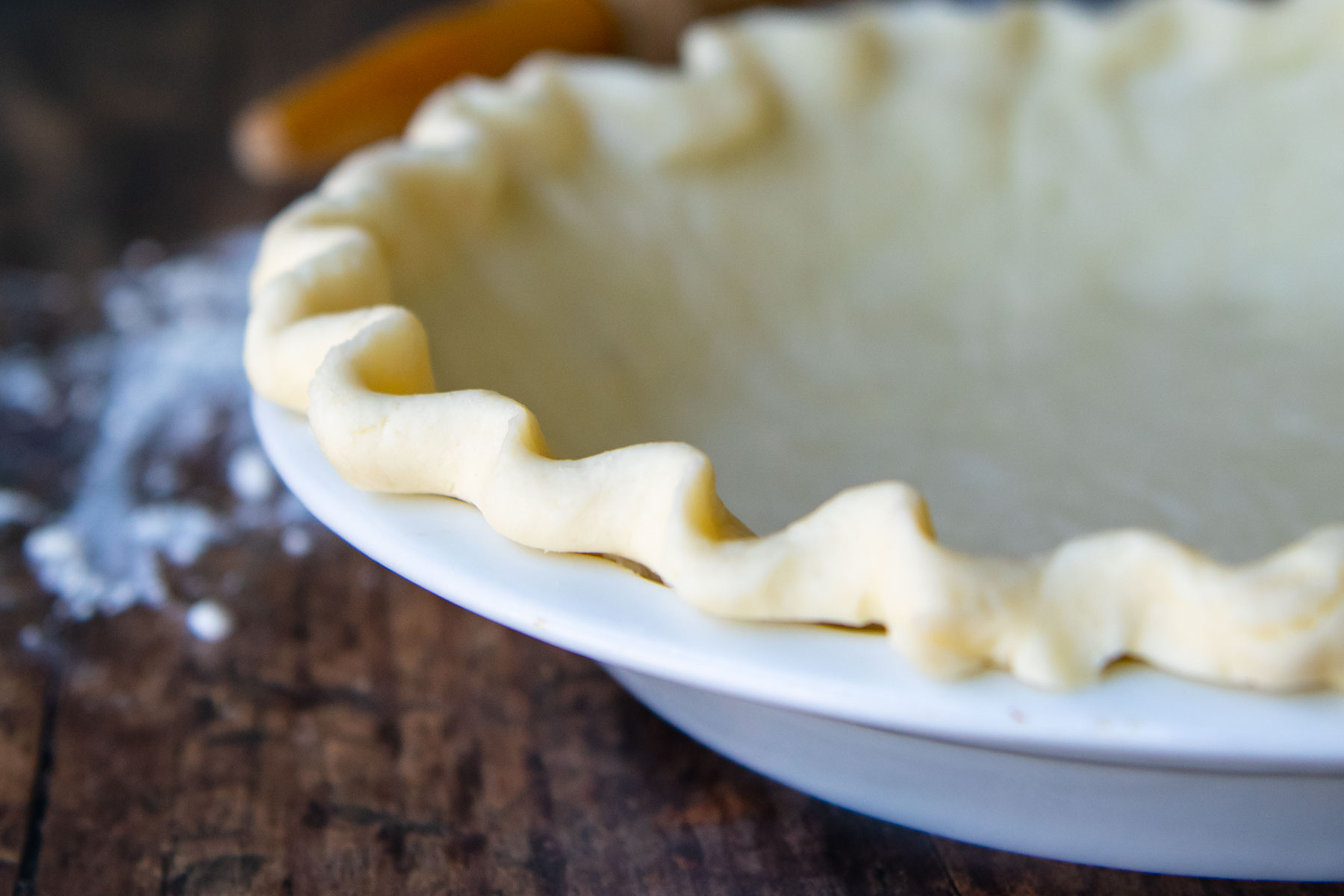 a horizontal image of unbaked gluten-free pie crust in a white pie plate