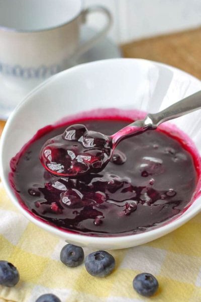 a bowl of blueberry syrup with a spoon resting on side