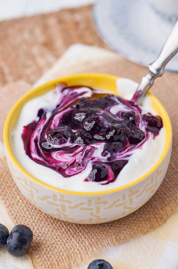 blueberry syrup swirled into a small bowl of yogurt