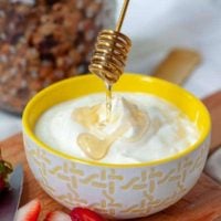 a honey spoon drizzling over a bowl of homemade instant pot yogurt