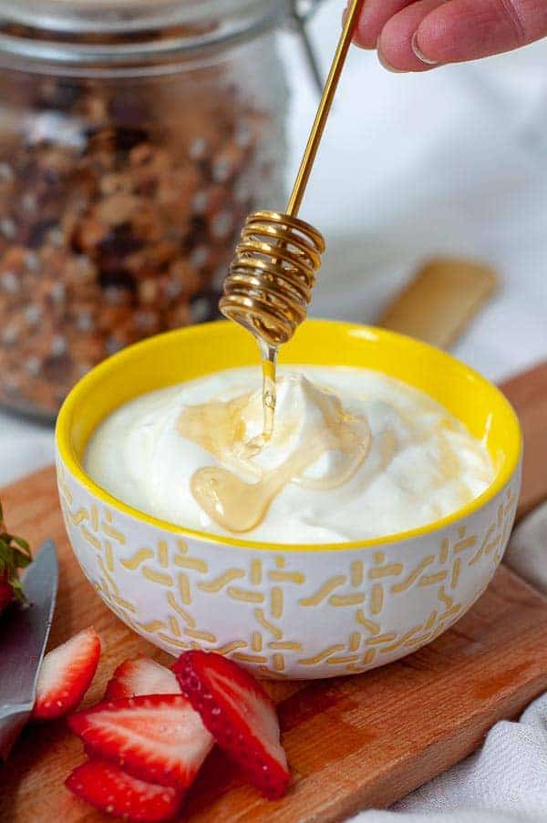 a honey spoon drizzling over a bowl of homemade instant pot yogurt