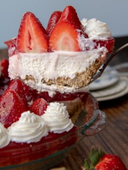 a slice of no bake strawberry cheesecake being lifted out a pie plate