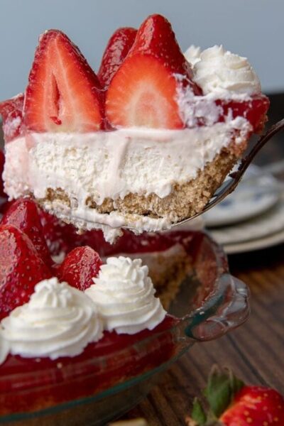 a slice of no bake strawberry cheesecake being lifted out a pie plate
