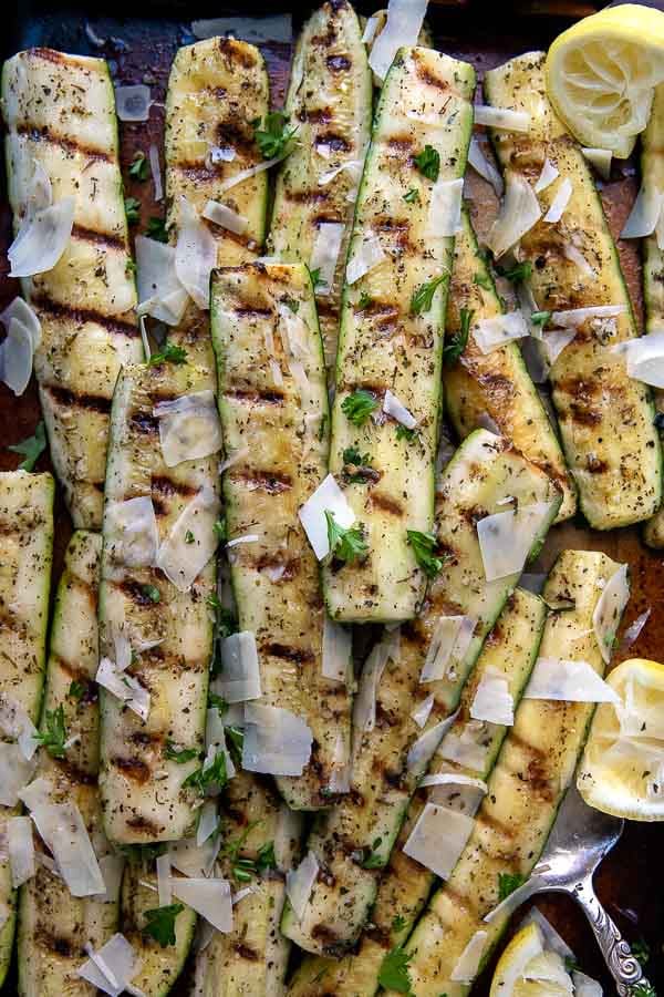 overhead shot of grilled zucchini and squash on a sheet pan with a serving utensil underneath.