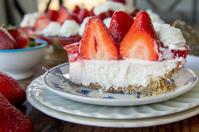 a cut slice of no bake strawberry cheesecake on a stack of white plates