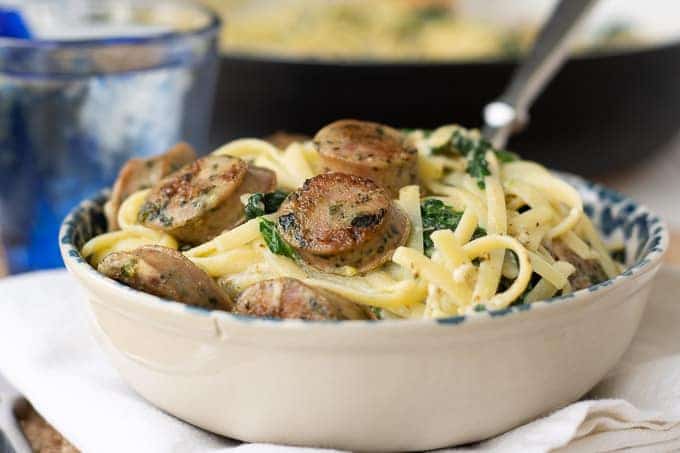 a bowl of creamy sausage pasta with a fork going in