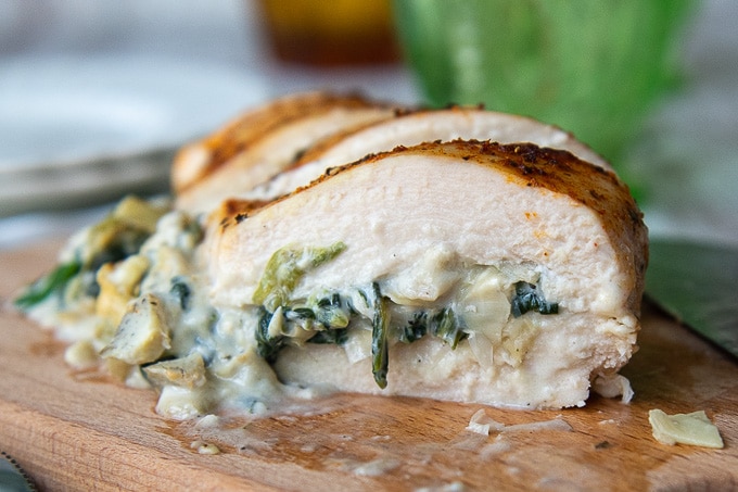 a stuffed chicken breast cut in half and a close up view of the spinach filling
