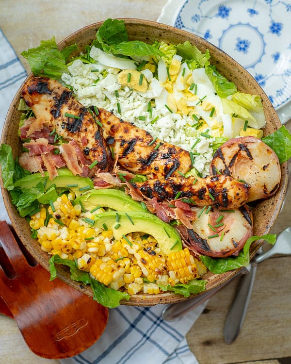overhead shot of grilled chicken salad with plates nearby