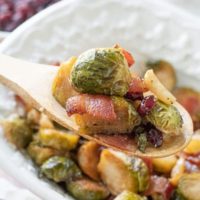 a wooden spoon lifting out a scoop of bacon brussels sprouts