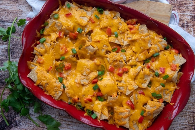 a mexican casserole in a red dish with cilantro next to it