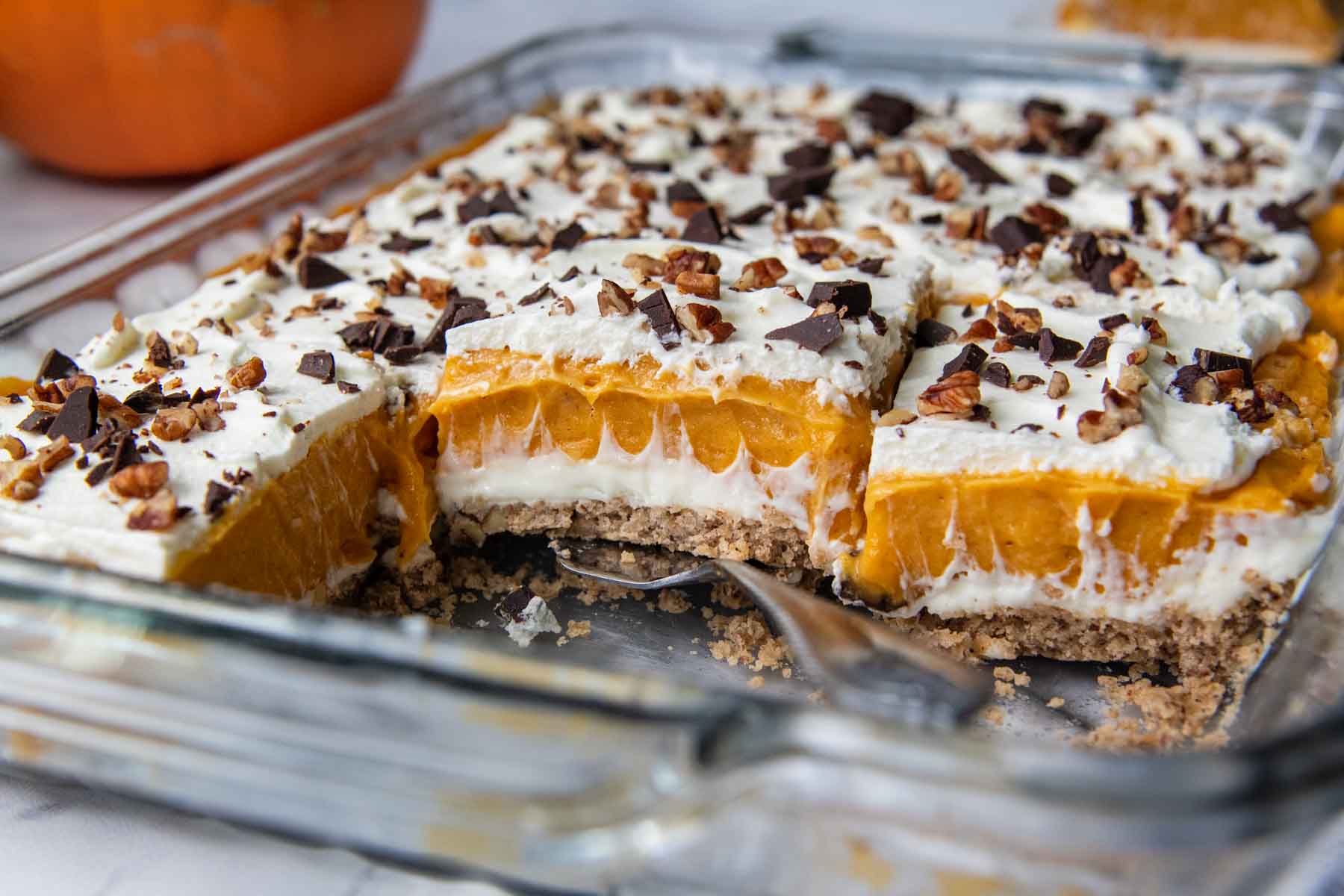 horizontal view of layered pumpkin lush with a spatula lifting a piece out