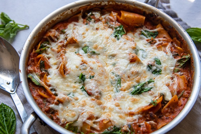 landscape image of one pan lasagna with melted cheese and spinach on top