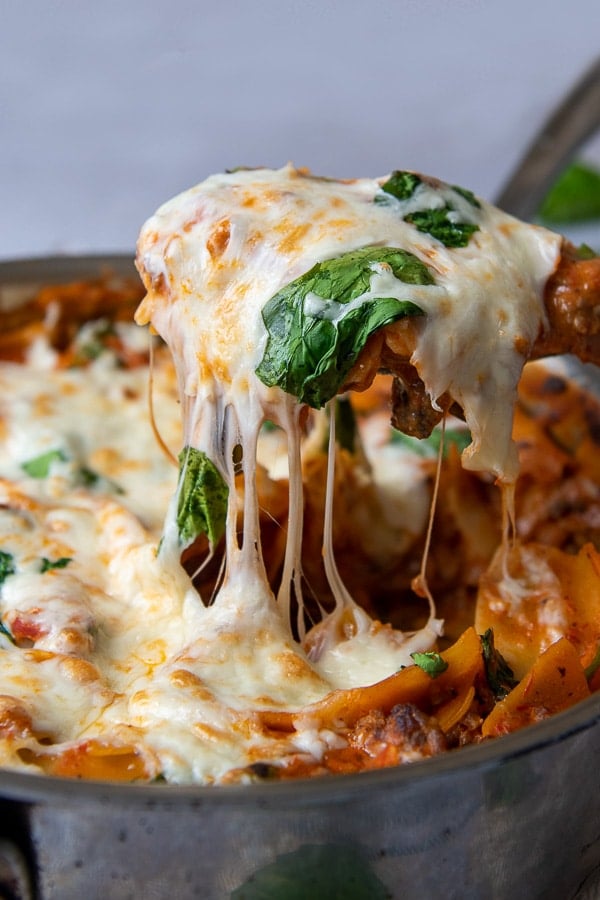 a spatula pulling up a serving of skillet lasagna with cheese dripping down