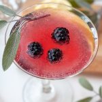an overhead shot of a blackberry martini with a sage leaf resting on top