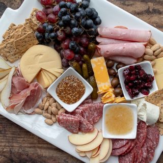 an overhead shot of a charcuterie board with plates nearby