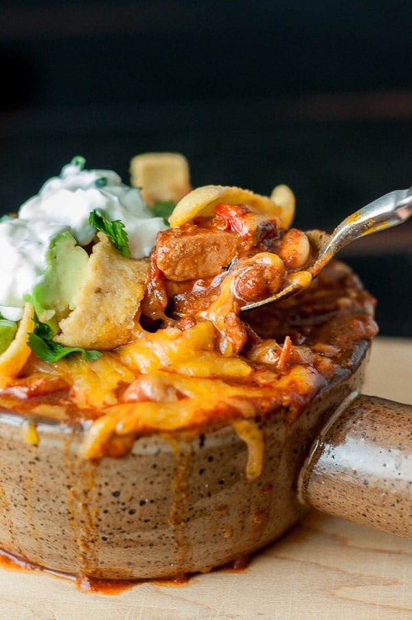 a close up of a spoon taking out a bite of chicken chorizo chili with cheese 