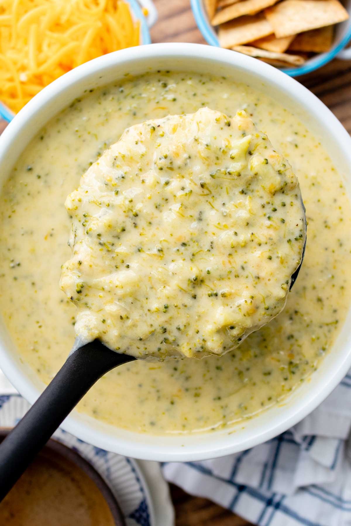 overhead shot of a ladle holding up broccoli cheese soup