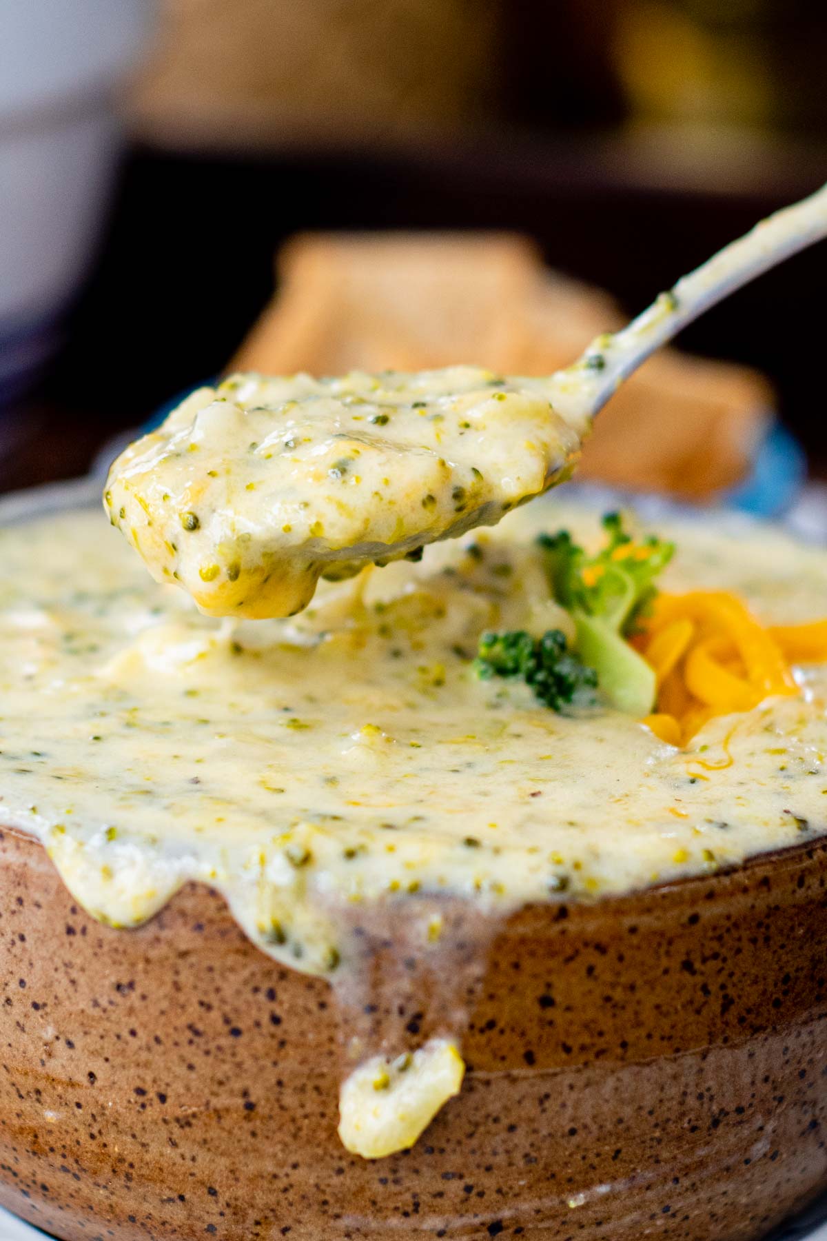 a spoon holding up a bite of broccoli cheddar soup