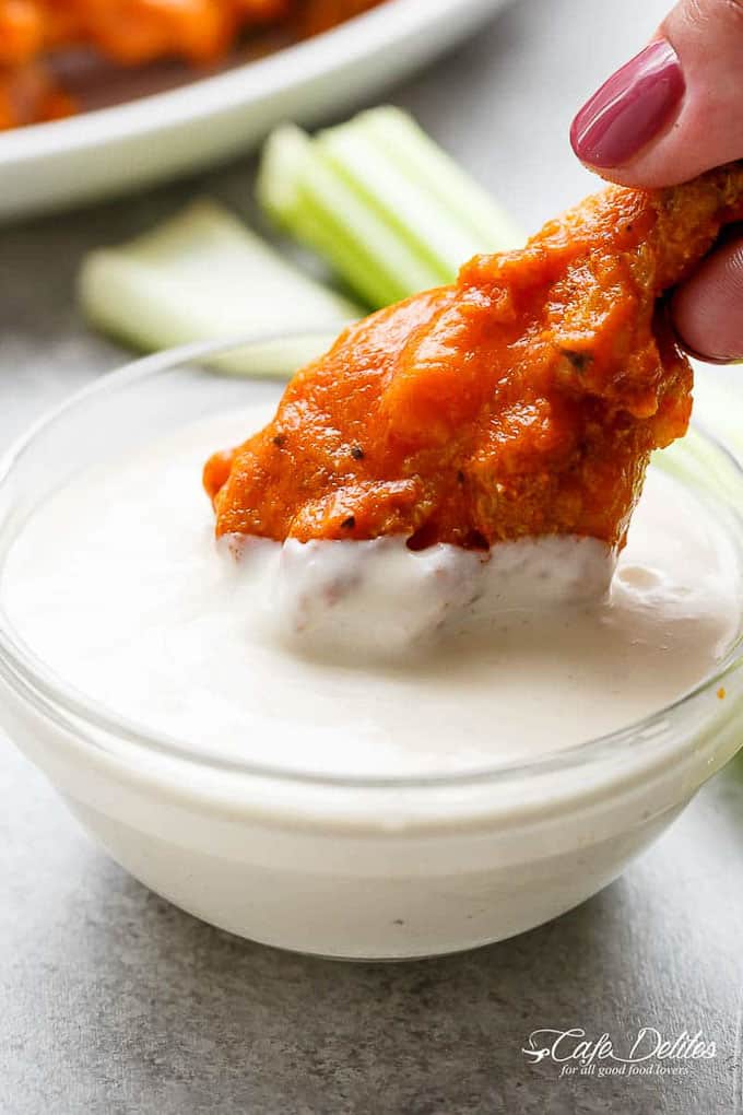 a buffalo chicken wing being dipped into dressing