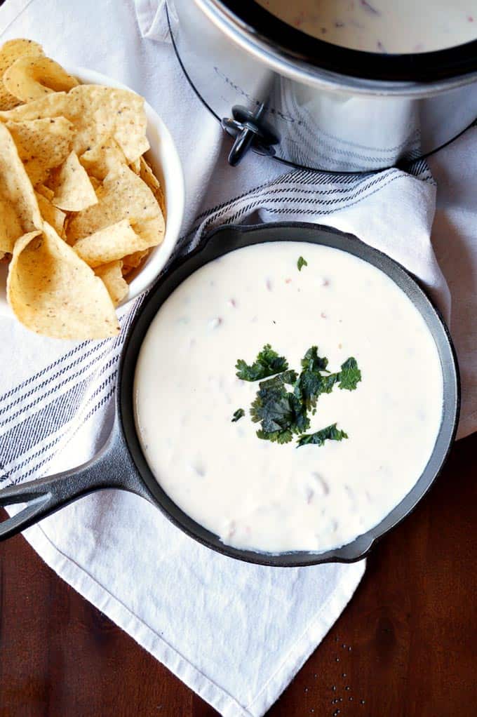 an overhead shot of white queso dip with a bowl of chips next to it for a super bowl party food appetizer